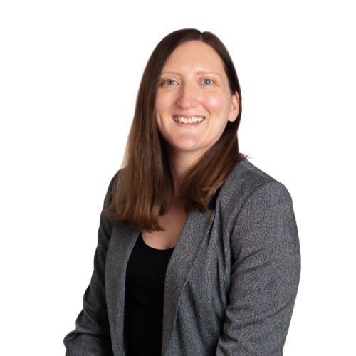 A woman wearing a grey jacket and black shirt smiles for the camera