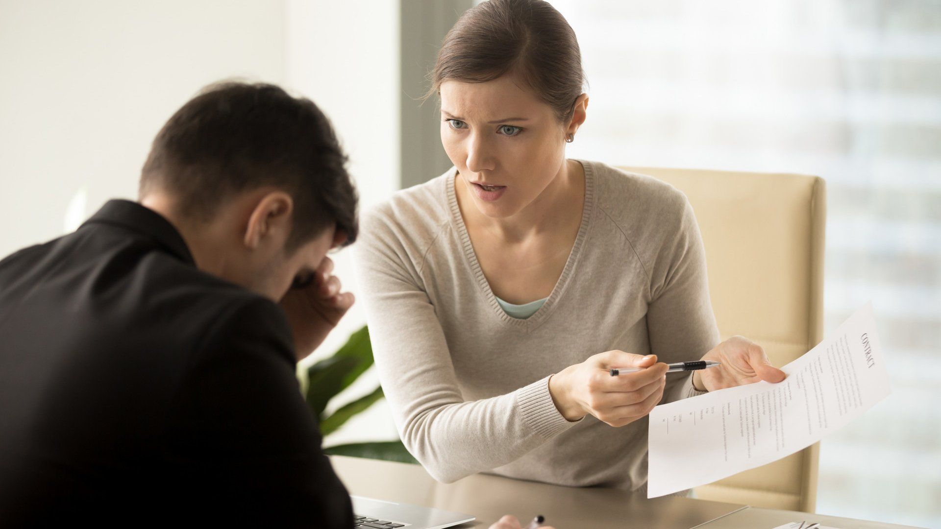A woman is talking to a man while holding a piece of paper.