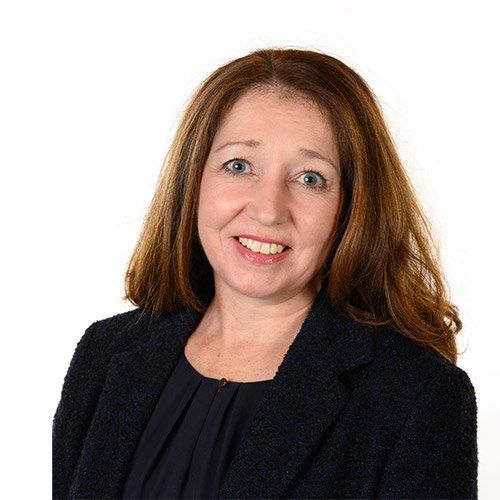 A woman in a black jacket is smiling for the camera.