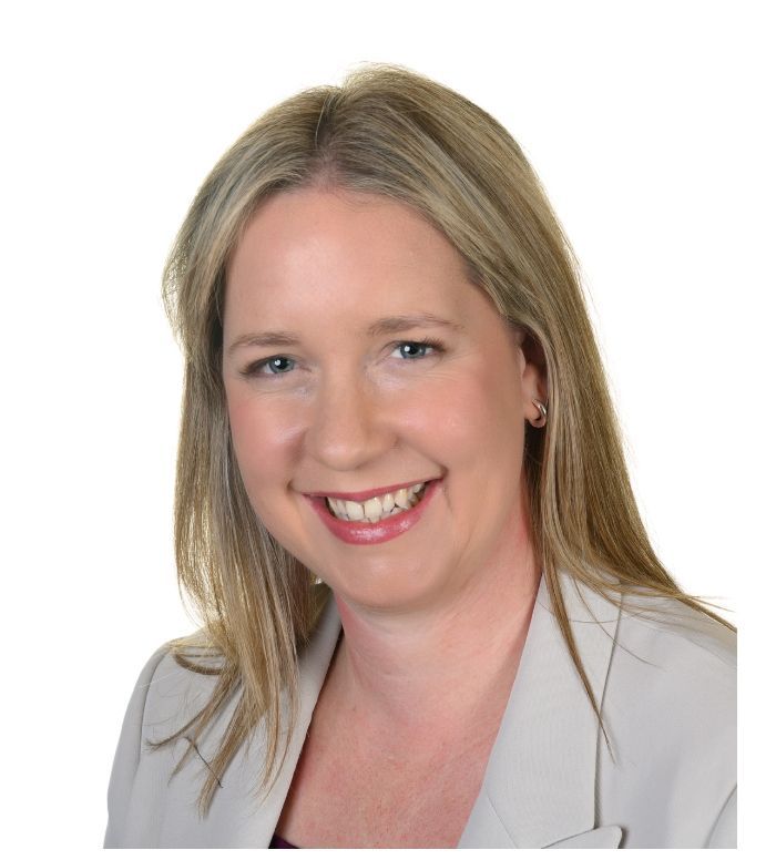 A woman in a grey jacket is smiling for the camera