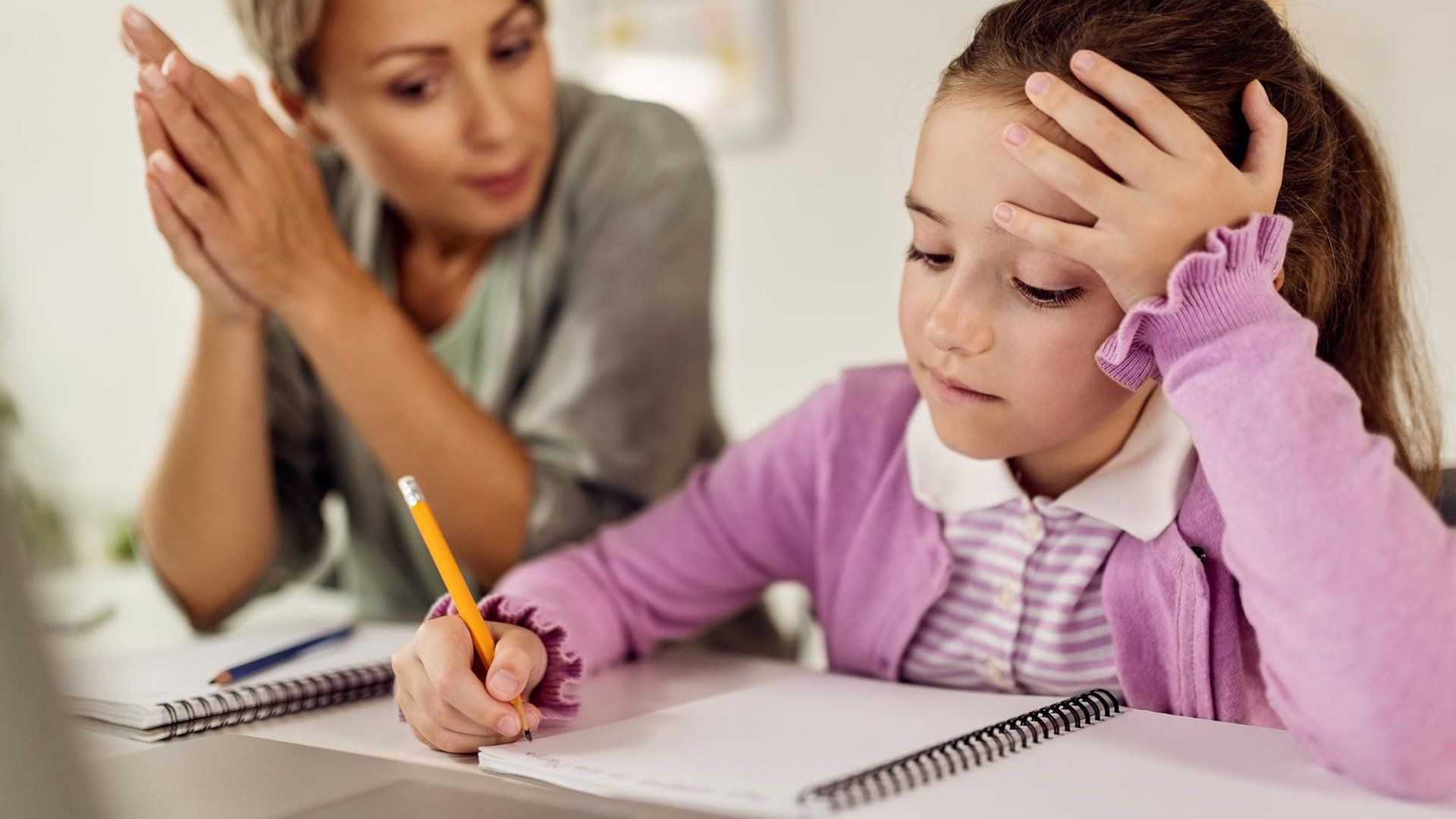 A woman is helping a little girl with her homework.