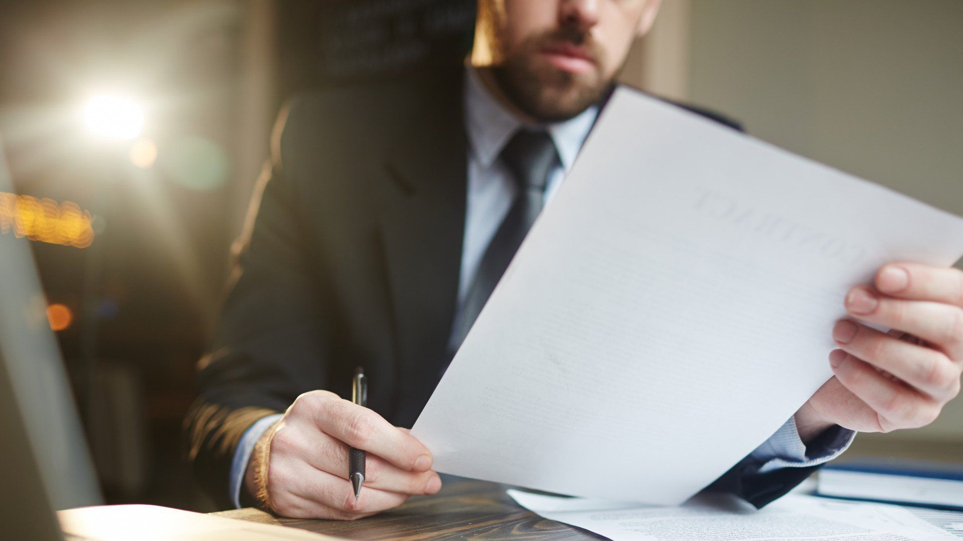 A man in a suit and tie is holding a piece of paper and writing on it.
