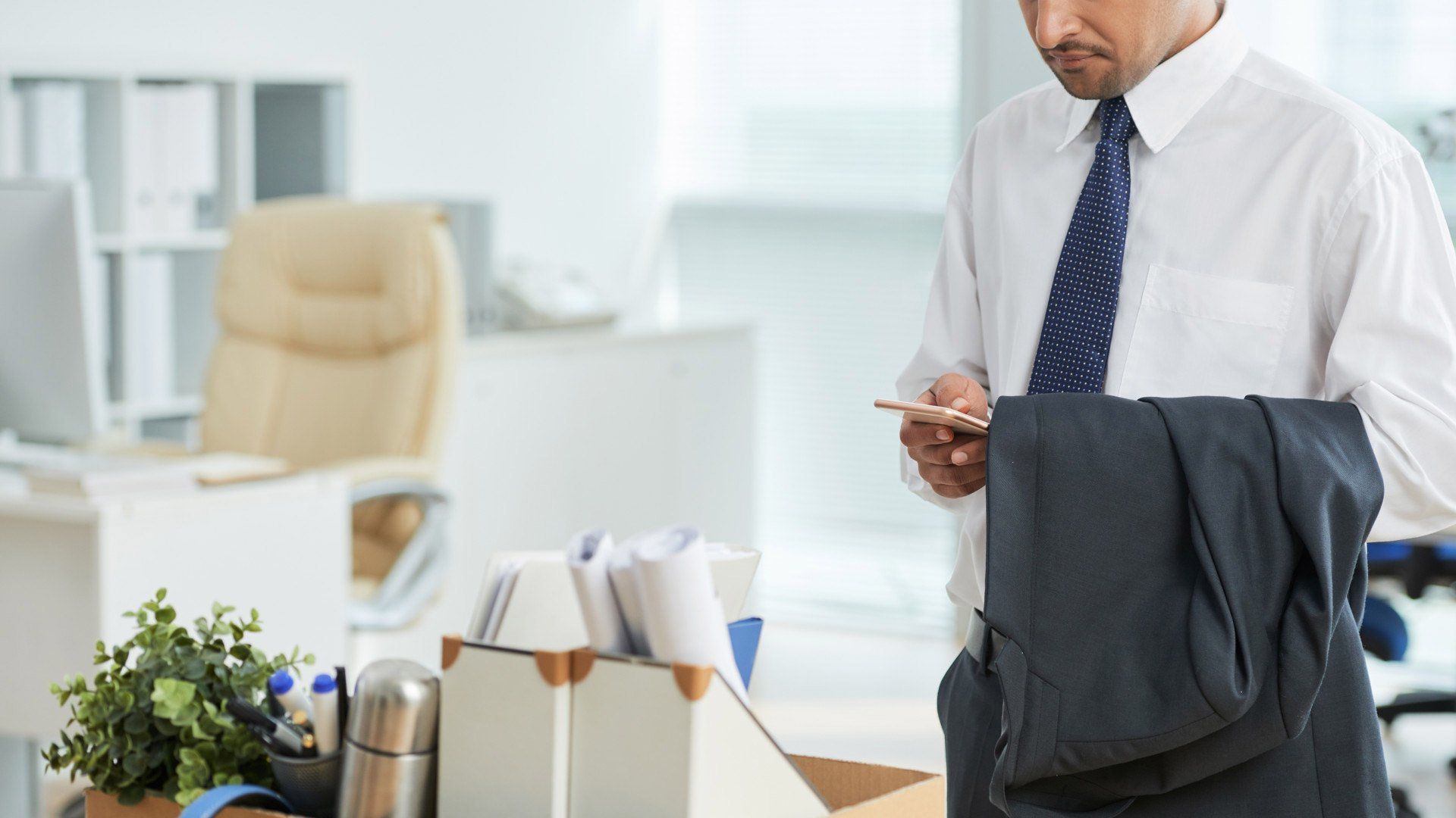 A man is standing in front of a box of his belongings in an office.