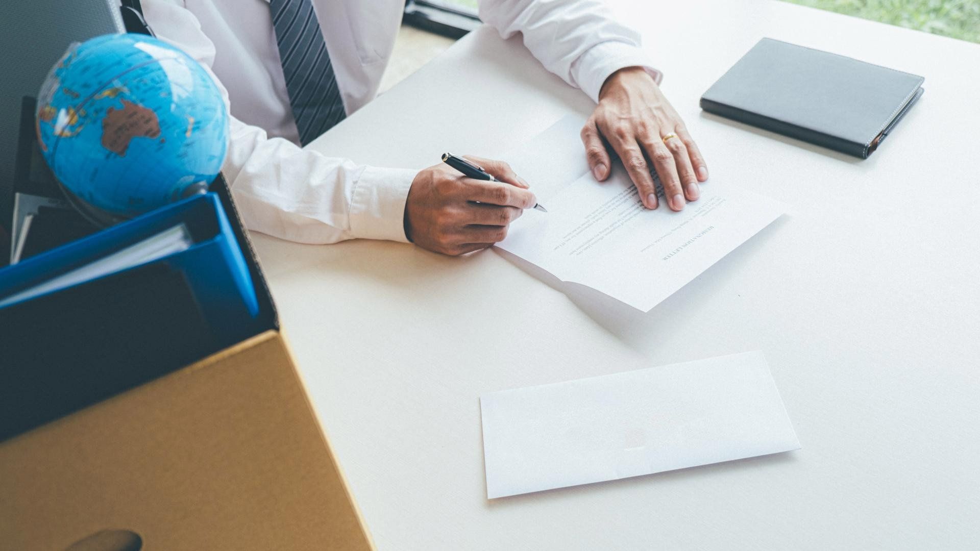 A man is sitting at a desk writing on a piece of paper.