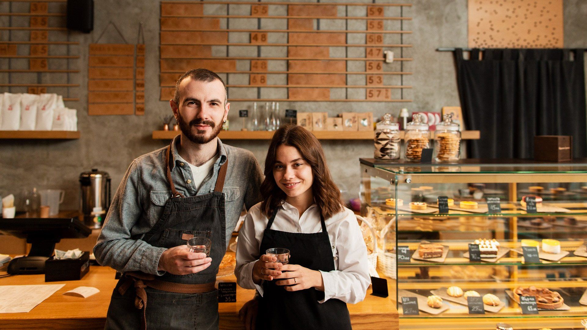 A man and a woman are standing next to each other in a coffee shop.