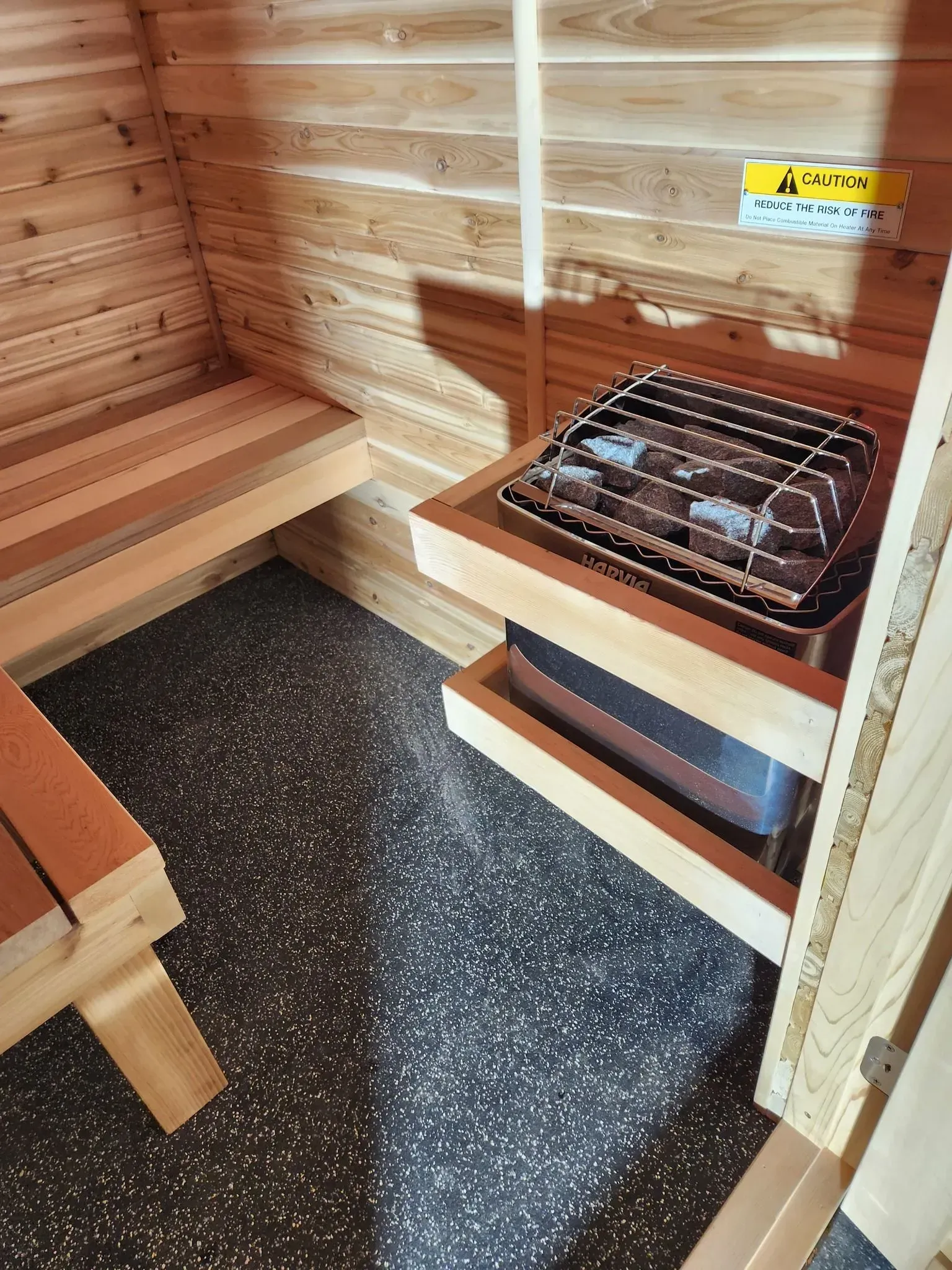 A wooden sauna with a stove and a bench.