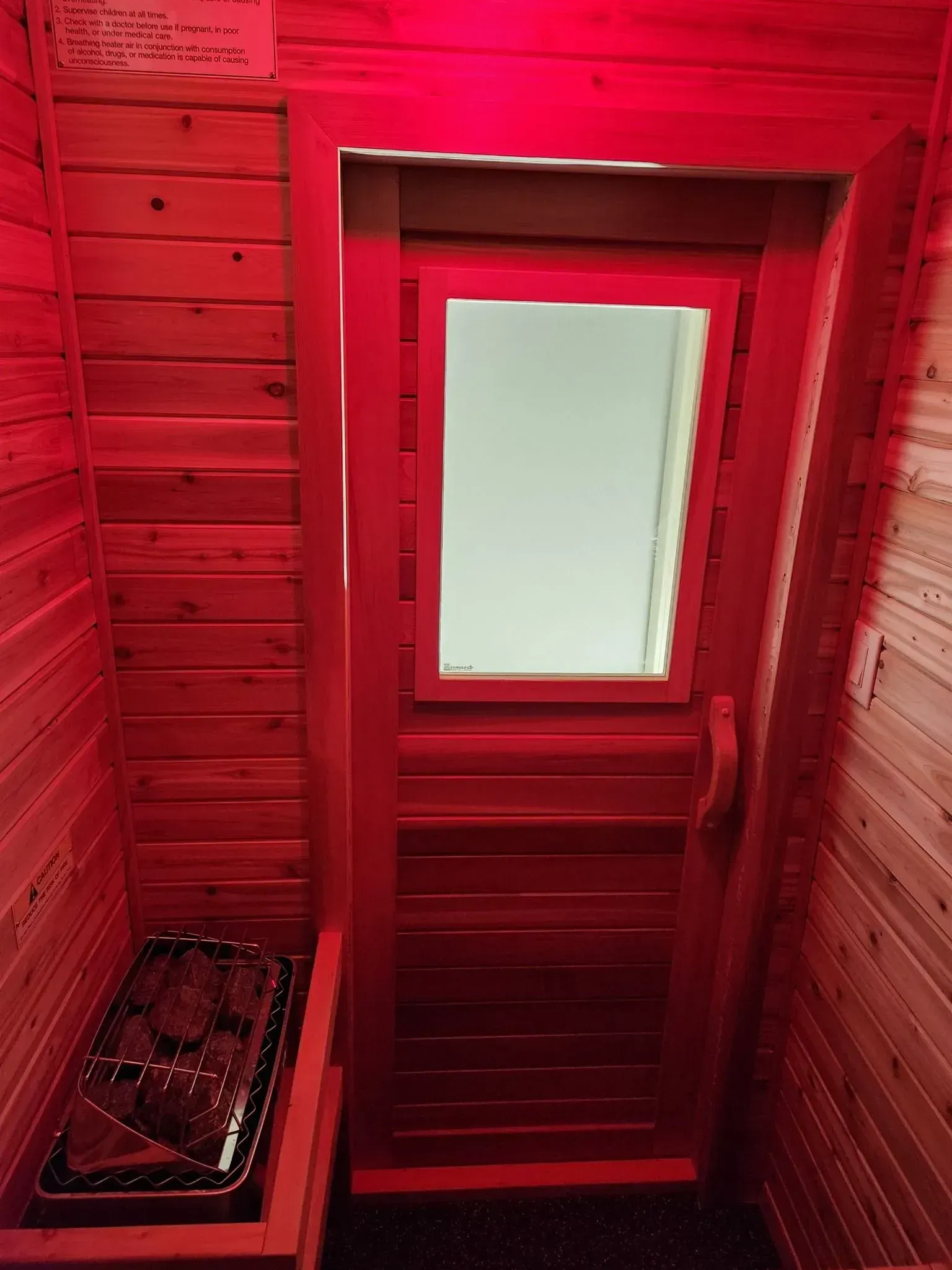 A wooden sauna with a red light on the door.