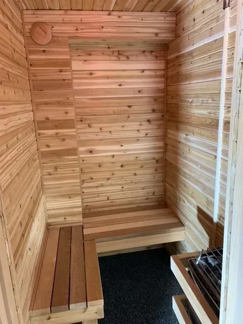 A small wooden sauna with a bench and a door.