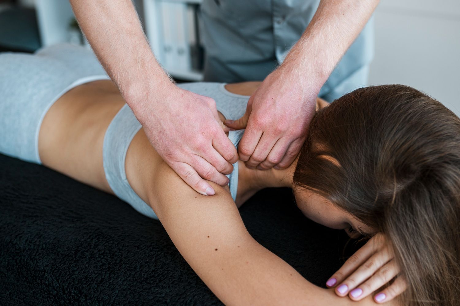 Therapist performing back massage on a person lying face down on a table