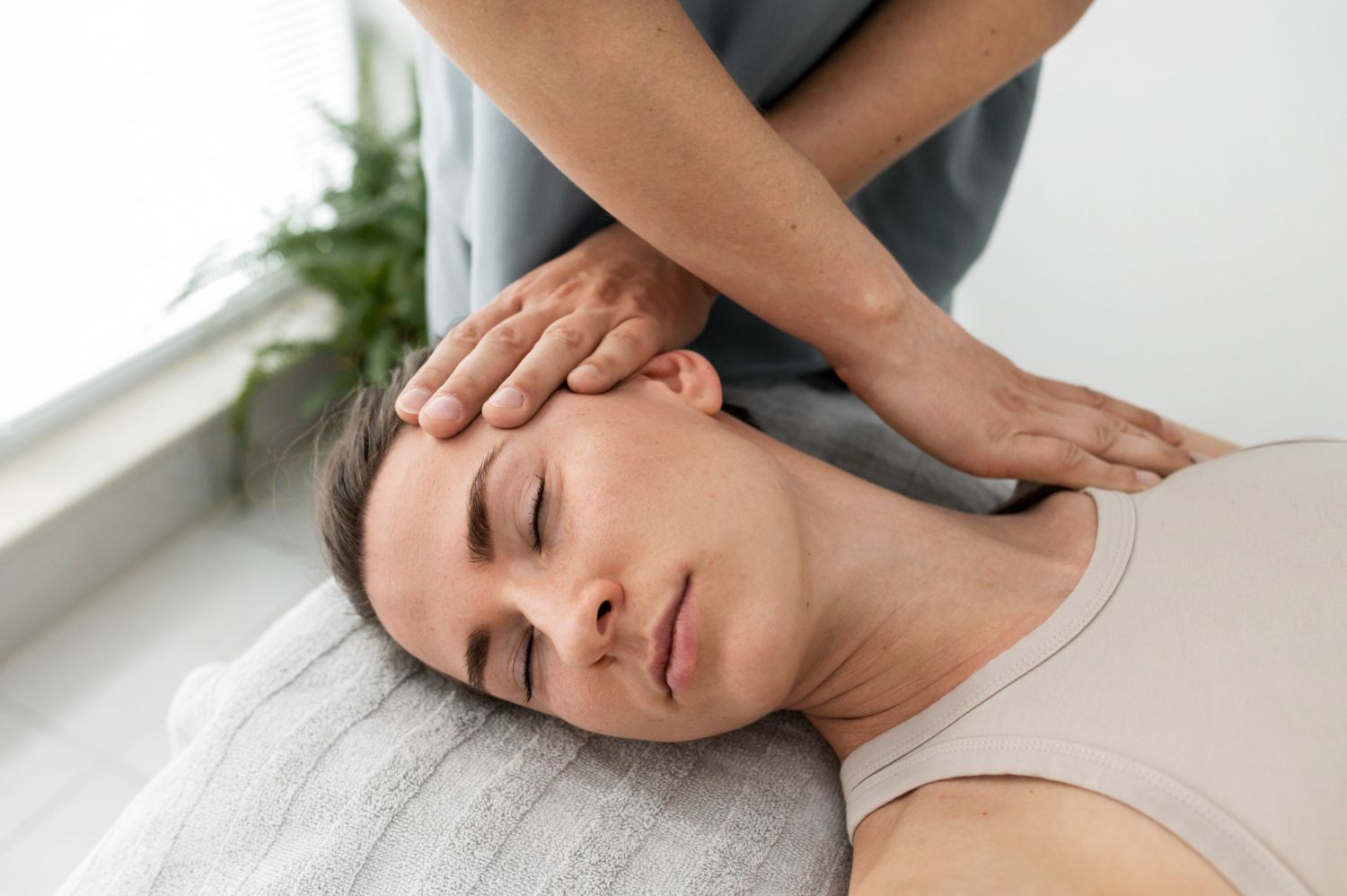 Massage therapist gently massages a woman's head and neck on a treatment table