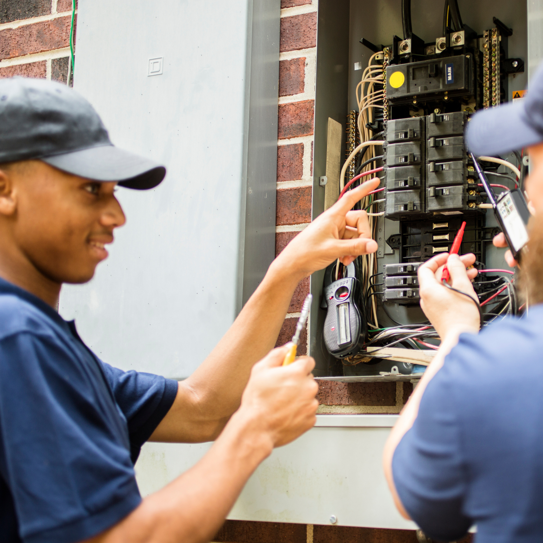 a man in a black hat is working on an electrical box
