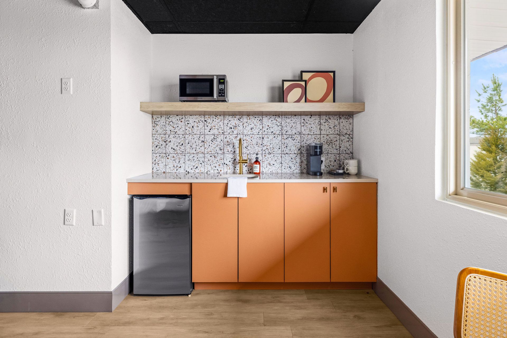 A kitchen with pink cabinets , a sink , and a coffee maker.