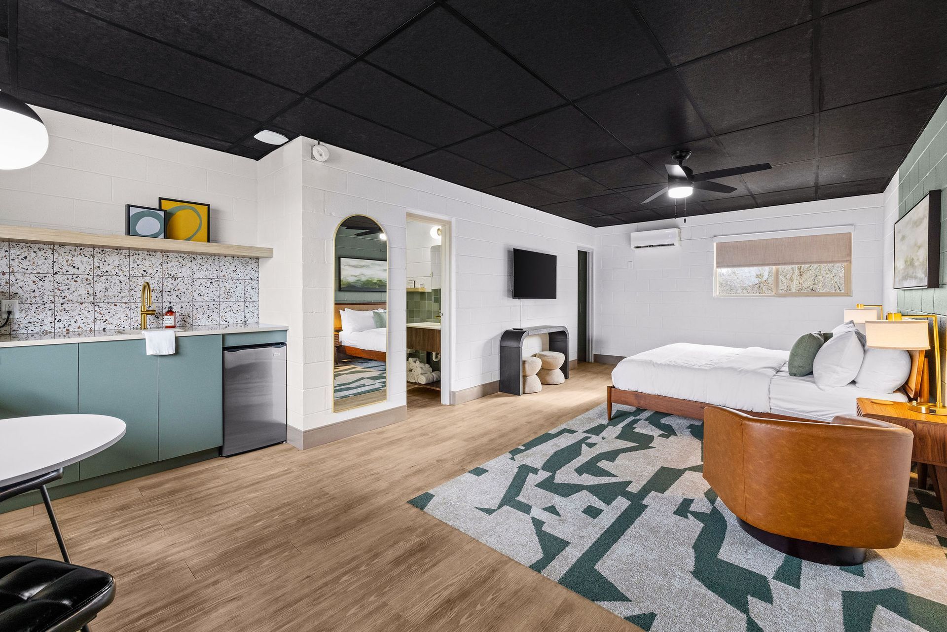 A picture of the entire room that includes the bed, accent chair, kitchenette, and dining table.