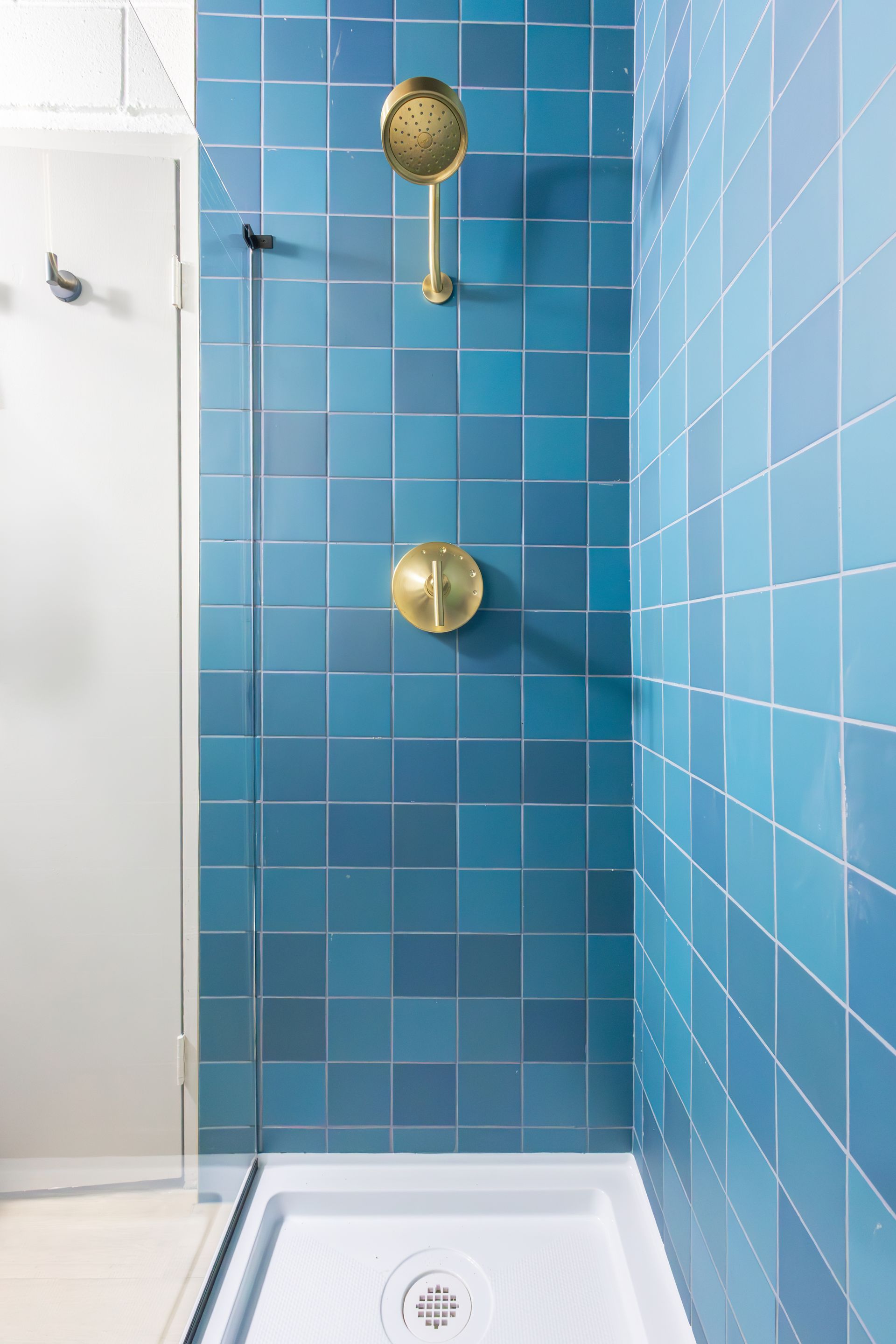 The shower with blue tile and gold shower hardware.