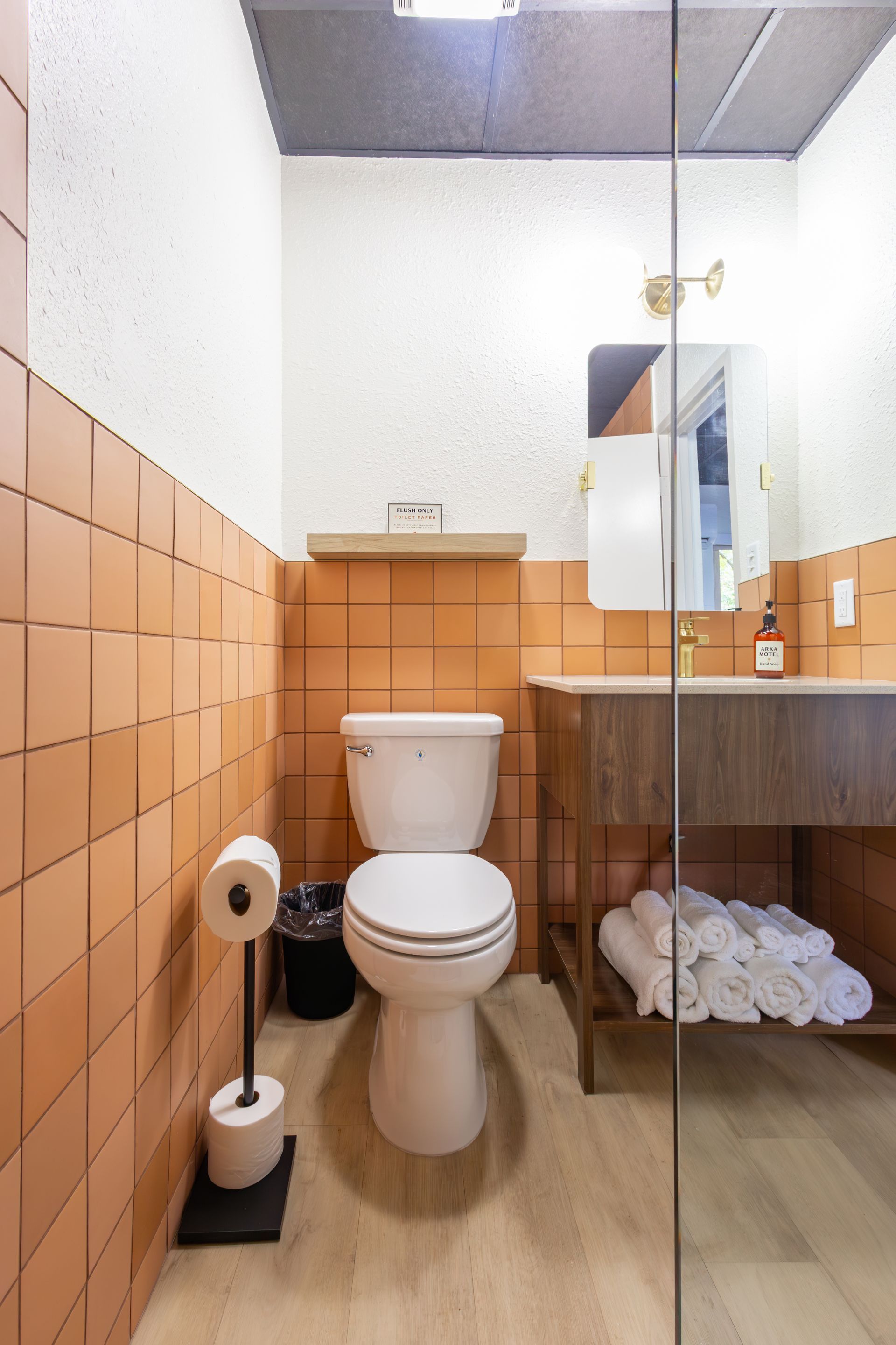 A bathroom with terracotta colored tile and a wooden modern vanity.