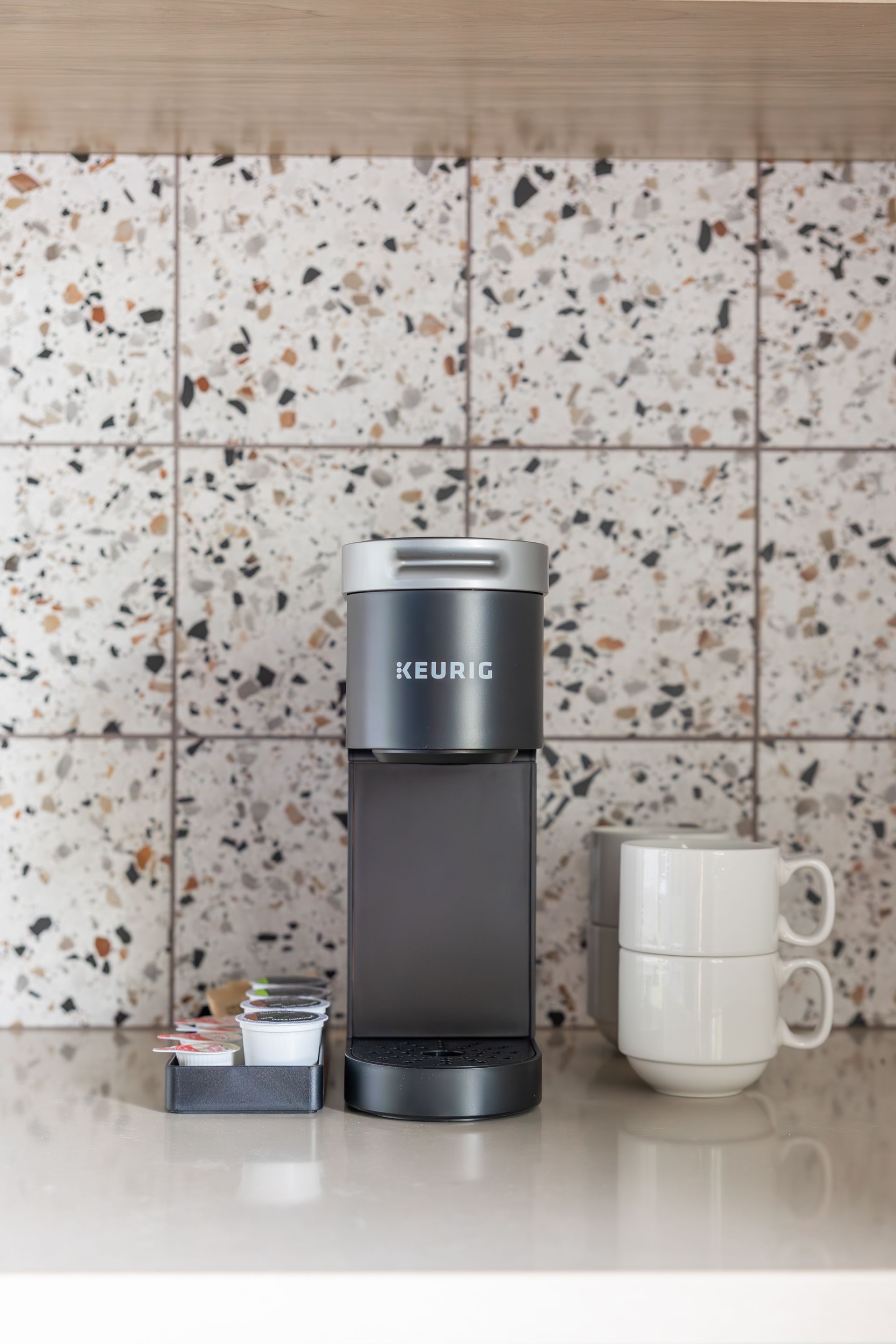 Keurig coffee maker and white coffee cups.
