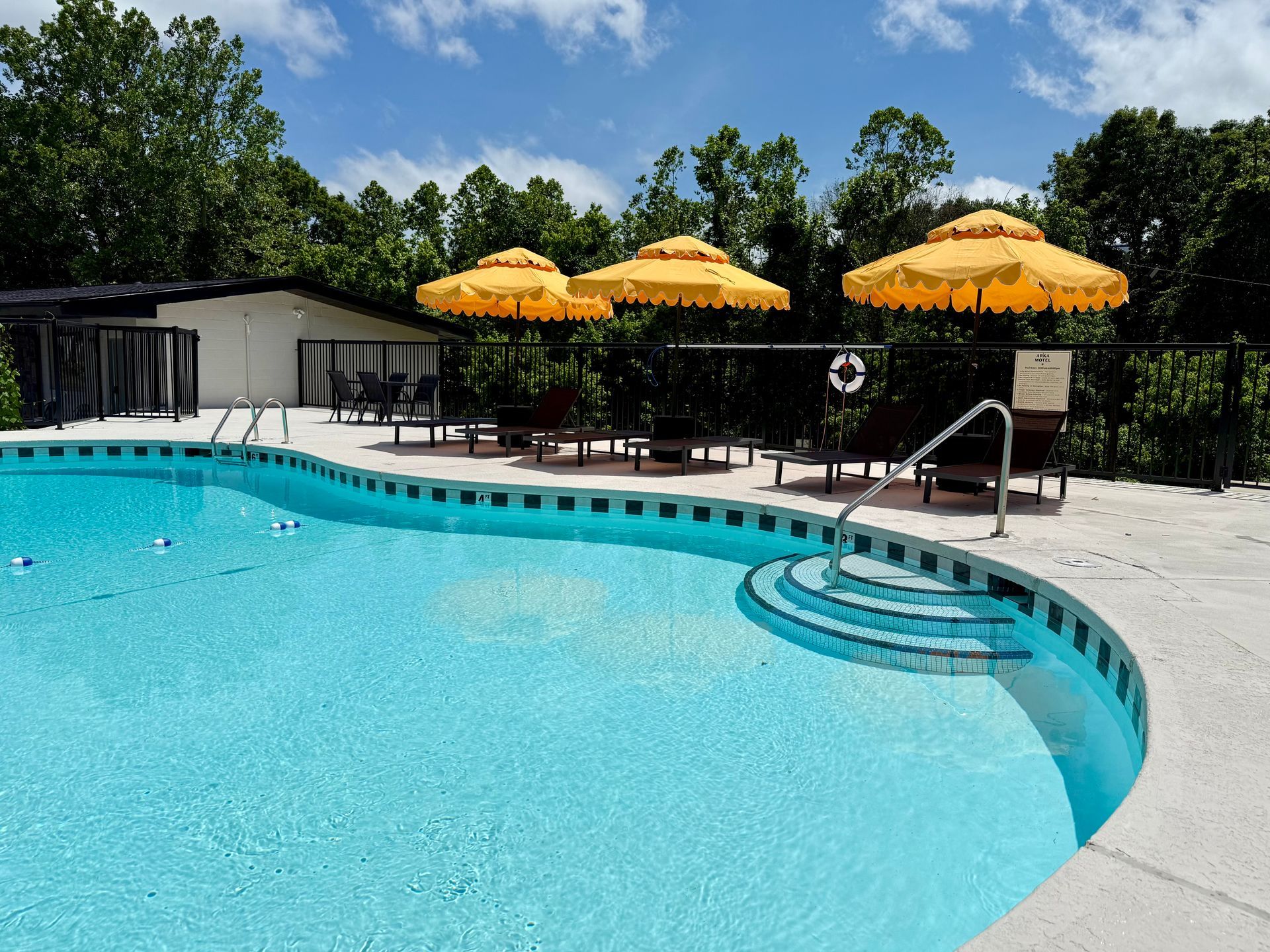 A large swimming pool surrounded by yellow umbrellas and chairs