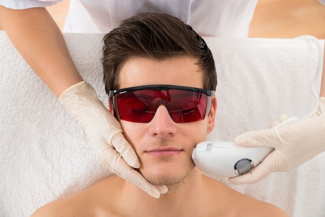 Persona recibiendo un tratamiento facial mientras usa gafas protectoras rojas.