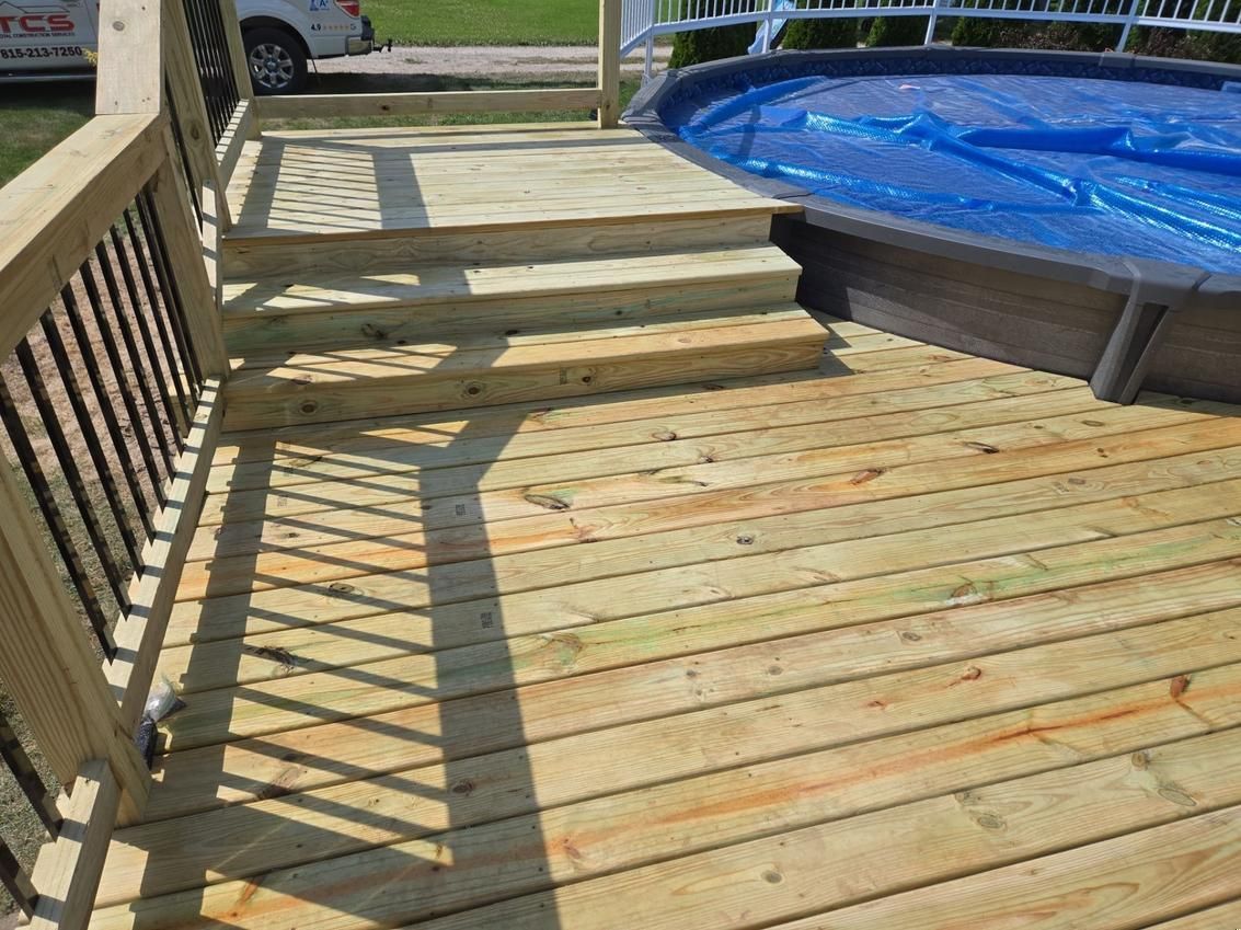 Wooden deck with steps leading down to an above-ground pool with a blue cover.