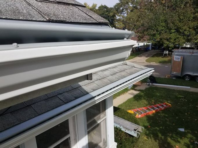 Gray gutters on a house with gray shingles, viewed from above, on a sunny day.