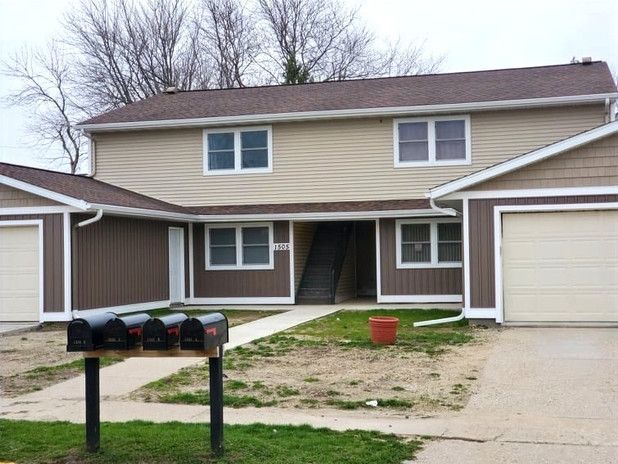 Suburban townhouse with beige siding, two garages, and black mailboxes in front