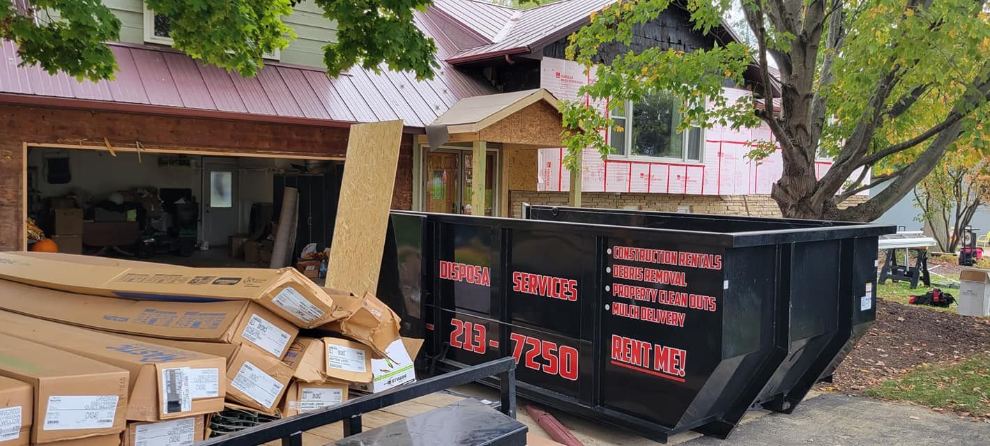 A house undergoing renovations with a dumpster and lumber in front.