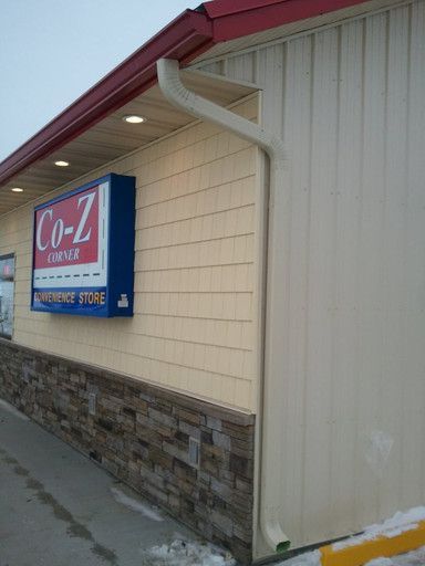 Exterior of a Co-Z Mart convenience store with a sign, beige siding, and stone facade base.