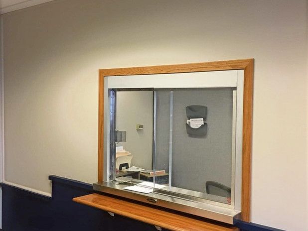 Window with a wooden frame and a stainless steel shelf, set in a light beige wall.