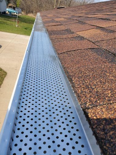 Metal gutter guard on a brown shingled roof.