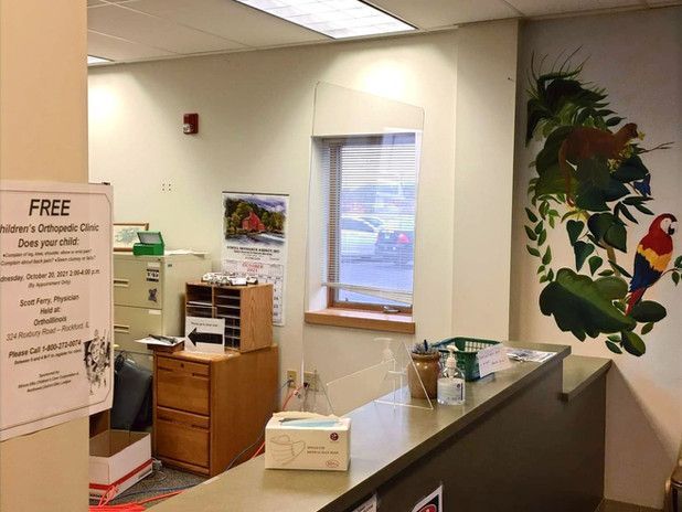 Reception area: desk, window, parrot mural, and signage.