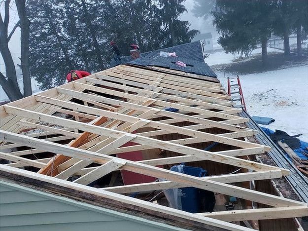 Roof partially rebuilt with exposed wooden rafters; snowy outdoor setting.