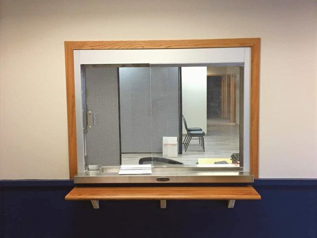 A service window with a wooden frame, and a shelf, on a blue and beige wall.