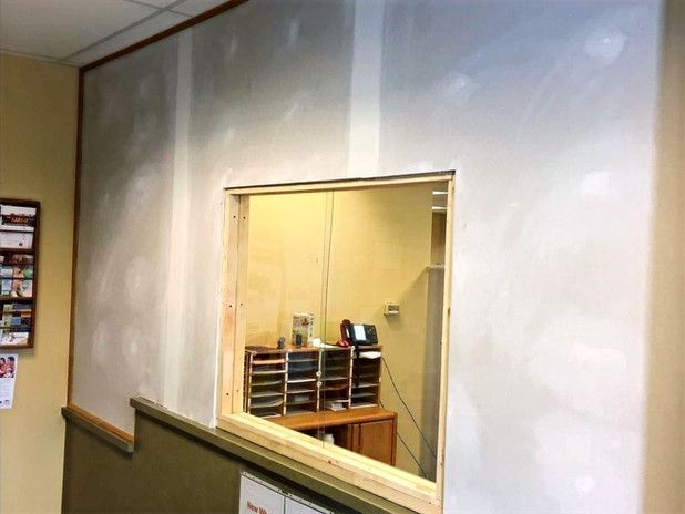Opening in wall with wooden frame, view of office with desk and phone.