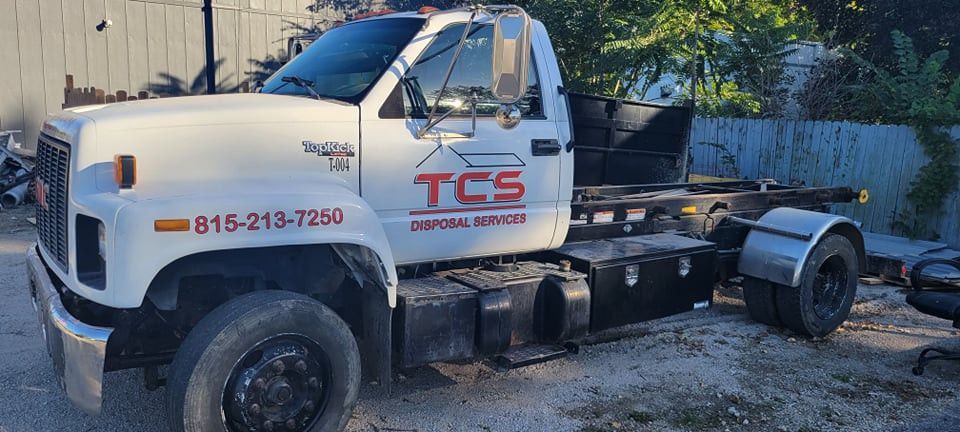 White TCS Disposal truck with black tires, parked outdoors. 816-213-7250 phone number on the side.