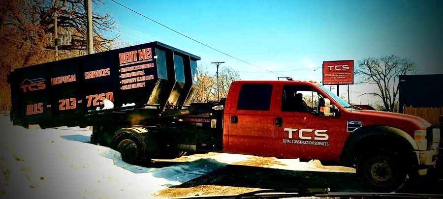 Red truck towing a dumpster with the logo