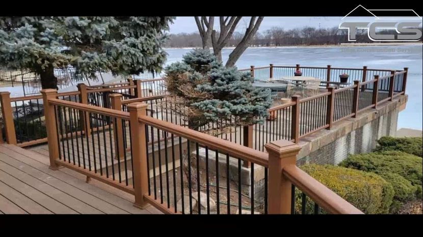 Deck with brown and black railings overlooking a body of water.