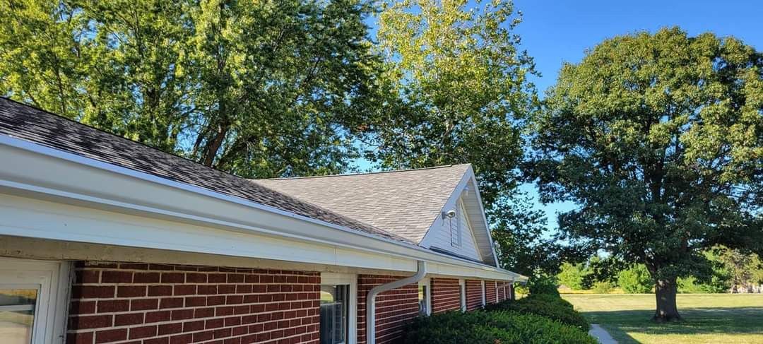Red brick building with white trim, trees, and blue sky.