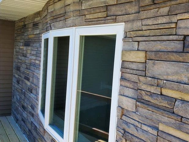 Exterior wall with stone veneer, white framed windows, and a wood-planked porch.