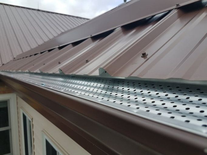 Brown metal roof with gutter guard attached to a home.