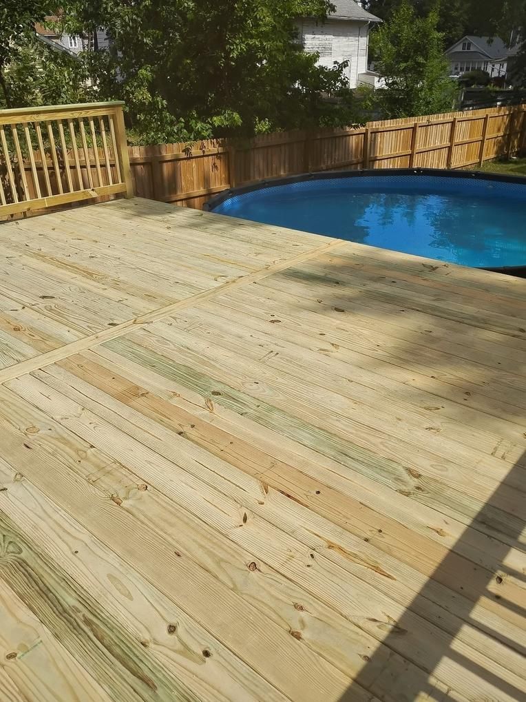 Wooden deck next to a blue above-ground pool, surrounded by a wooden fence.