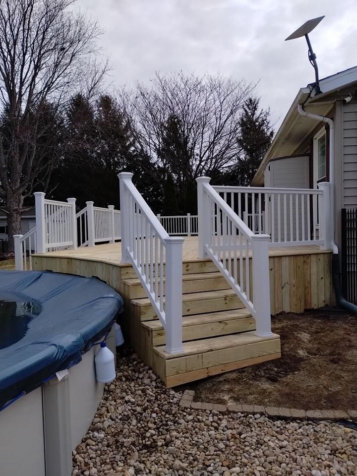 Wooden deck with white railings and stairs, next to a backyard with an above-ground pool.