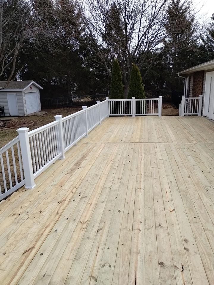 Wooden deck with white railings, a shed, and bare trees in the background.