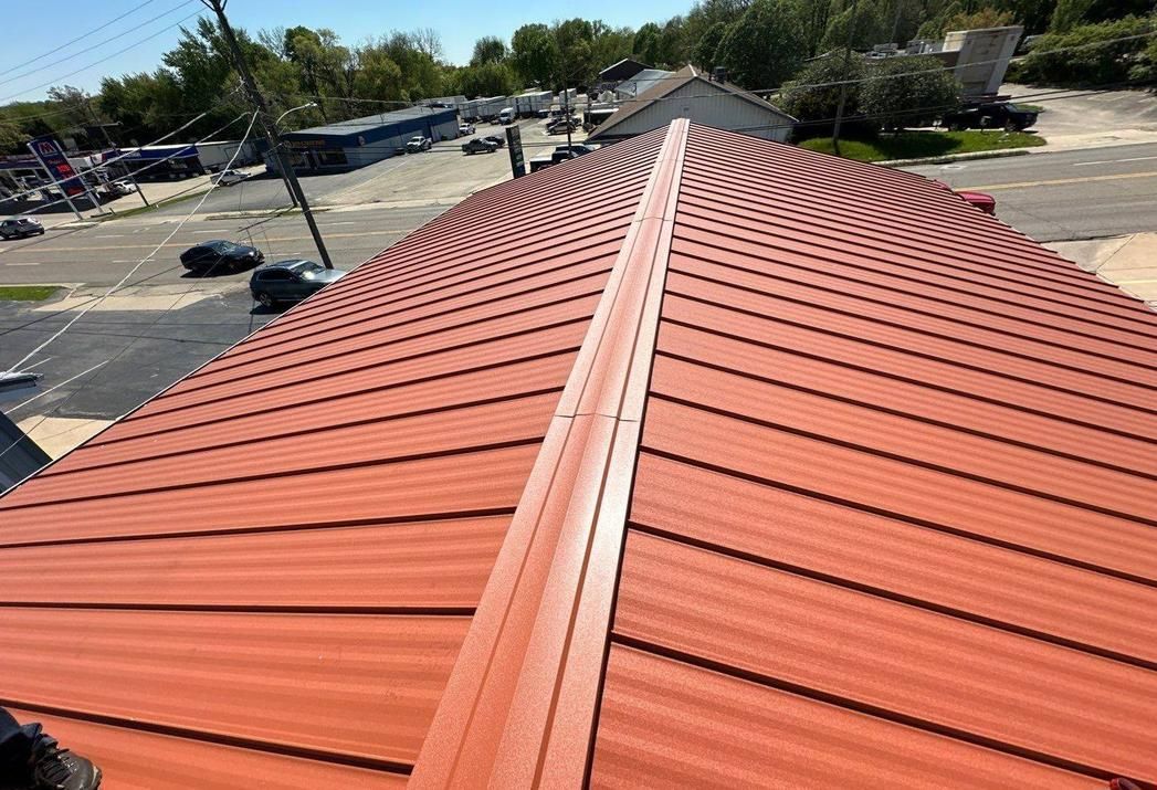 Red metal roof with white ridge cap viewed from above on a building site