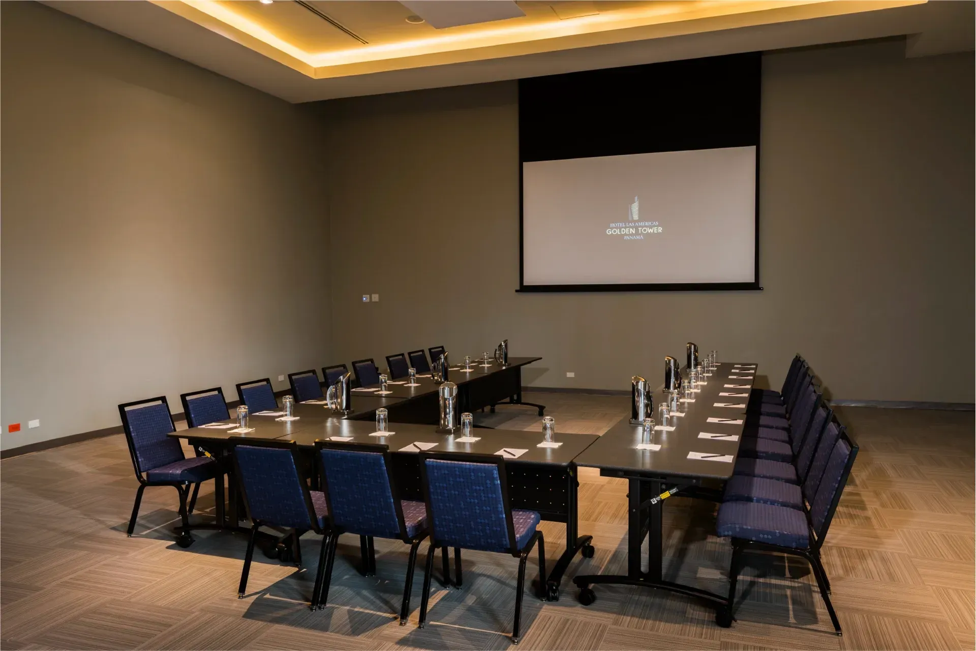 Una sala de conferencias con mesas y sillas y una pantalla de proyección.