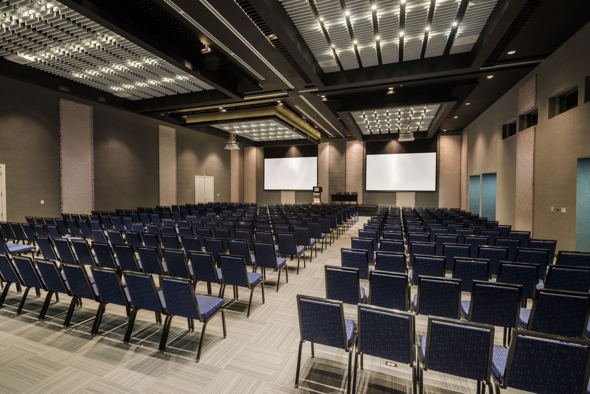 Un gran auditorio con sillas azules y un podio.