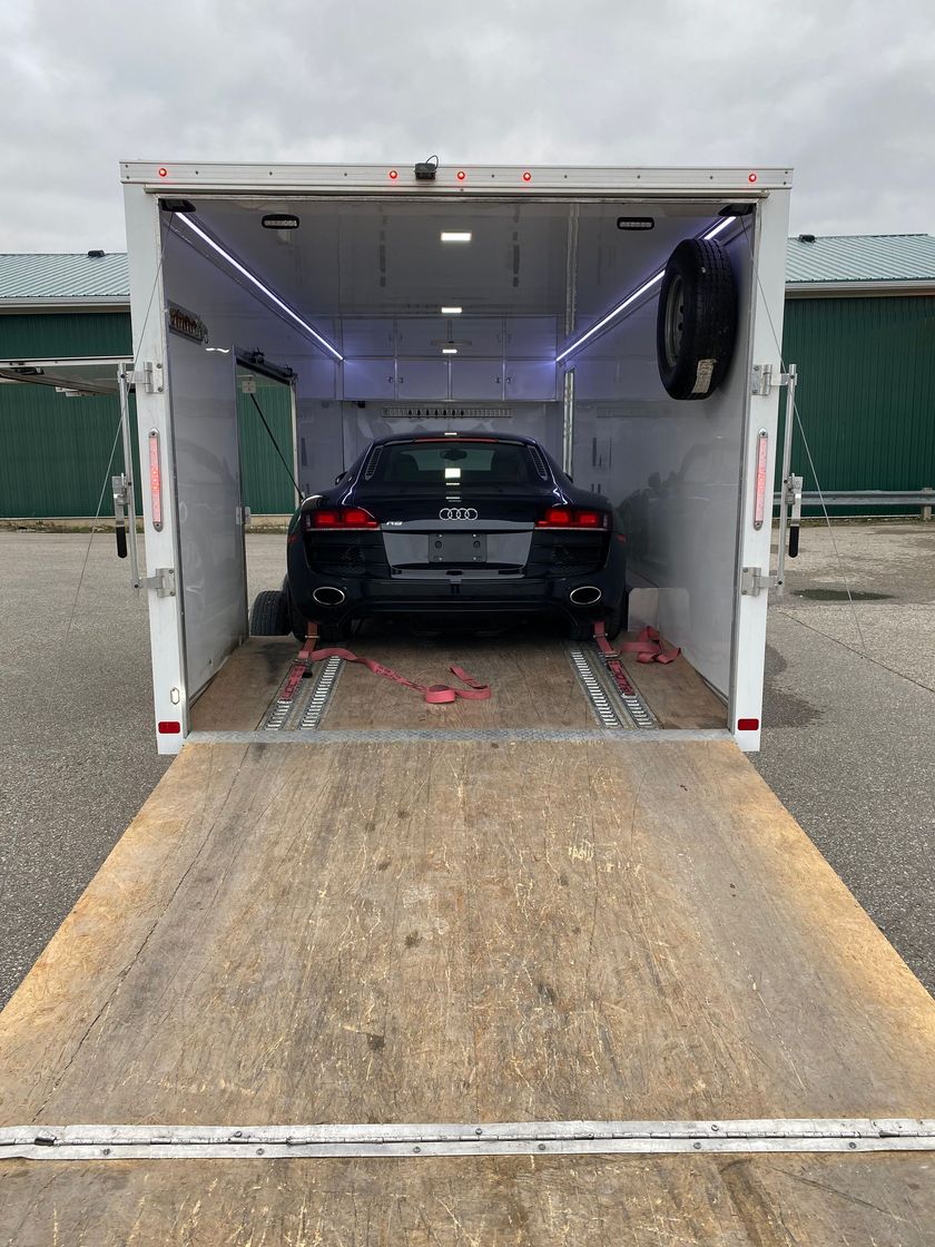 A black car is sitting inside of a trailer.