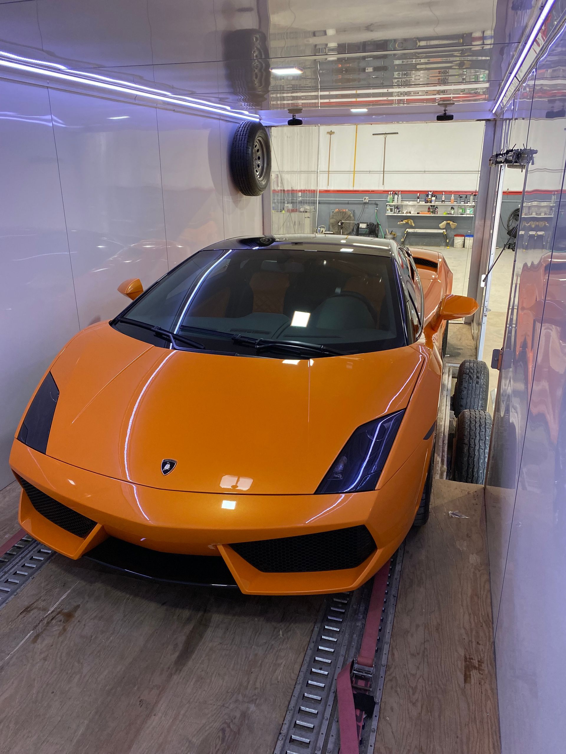 An orange lamborghini is parked inside of a trailer