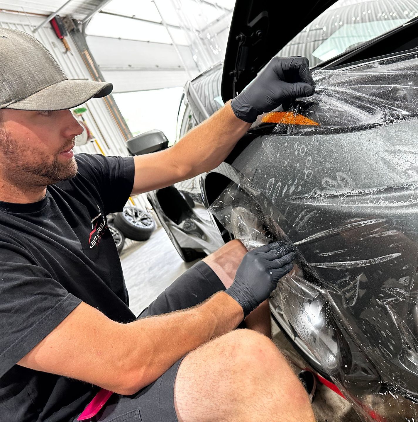 A man is applying a protective film to the headlights of a mercedes benz.