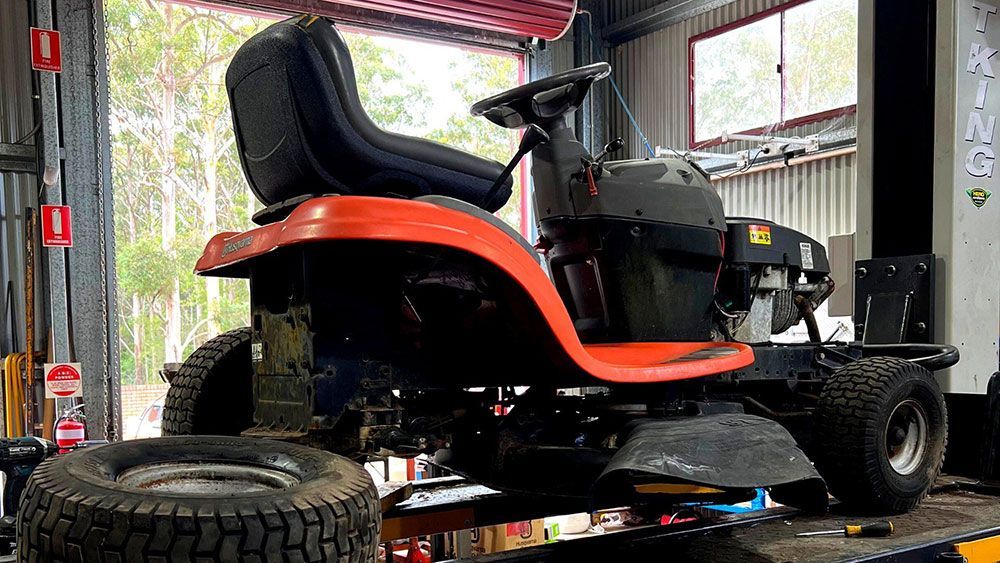 A Lawn Mower Is Sitting on A Lift in A Garage — CBS Chainsaw & Brushcutter Specialists - HUSQVARNA in Wauchope, NSW