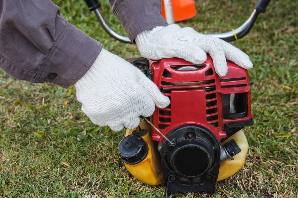 A Person Is Fixing a Lawn Mower with A Screwdriver — CBS Chainsaw & Brushcutter Specialists - HUSQVARNA in Comboyne, NSW